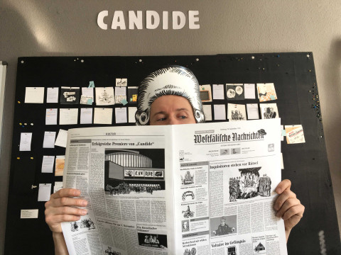 Robert Nippoldt liest eine Zeitung vor dem Storyboard für Candide